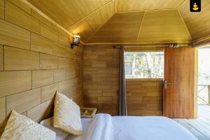 1 dormitorio con pared de madera, cama y ventana en LivingStone Shimla Jungle Stay, en Shimla