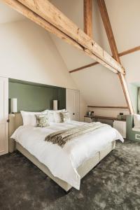 1 dormitorio con 1 cama blanca grande y cabecero verde en Raphaëlles Boutique b&b, en Brujas