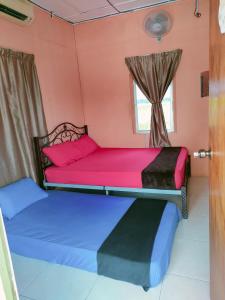 2 Betten in einem Zimmer mit Fenster in der Unterkunft Izz Homestay Sawah Padi Sungai Besar ! in Kampong Parit Ten