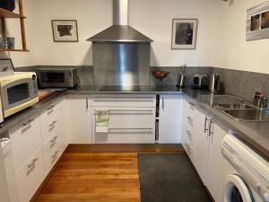a kitchen with white cabinets and a microwave at Beachside Taroona with Spa in Sandy Bay