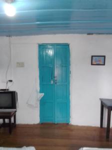 Una puerta azul en una habitación blanca con TV en Hostal Familiar Jerico, en Salento
