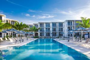 a pool with chairs and umbrellas in front of a building at The Capitana Key West in Key West