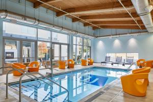 an indoor pool with orange chairs and a swimming pool at Aloft Dulles Airport North in Ashburn