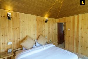 1 dormitorio con paredes de madera y 1 cama con almohadas en LivingStone Shimla Jungle Stay, en Shimla