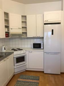 una cucina bianca con elettrodomestici bianchi e armadietti bianchi di Hannelen Varakoti a Loimaa