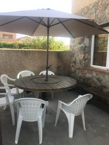 einen Tisch mit weißen Stühlen und einem Sonnenschirm in der Unterkunft Casas Encinares in Narrillos de San Leonardo