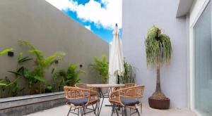 a patio with a table and chairs and a palm tree at Flat Encantador Bauten Cabo Branco in João Pessoa