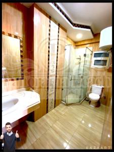 Un niño parado en un baño con lavabo y ducha en شقق بانوراما شاطئ الأسكندرية كود 2 en Alexandria