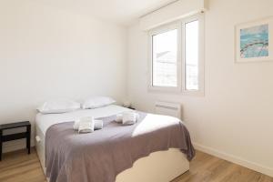 Un dormitorio blanco con una cama con toallas. en DIFY Bollier - Quartier Gerland, en Lyon