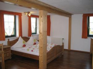 a bedroom with a wooden bed in a room with windows at Hotel Brückenmühle in Meiningen