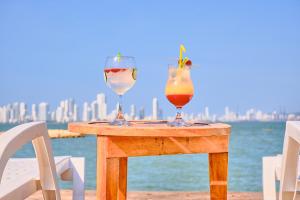 巴鲁岛Marazao Beach Hotel & Spa的坐在水边桌子上的两杯饮料