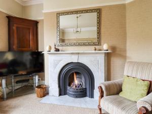 a living room with a fireplace and a mirror at Craven House in Skipton