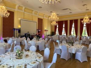 a banquet hall with white tables and chairs and chandeliers at Hotel Am Schloss Aurich - Schlossresidenz in Aurich