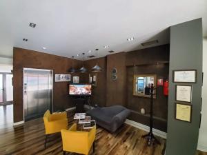 a living room with yellow chairs and a television at Hotel Alysa Korce in Korçë