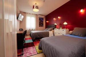 a red room with two beds and a desk and a desk at hotel de la paix in Pamiers