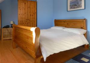 a bedroom with a wooden bed with white sheets at Castle Cottage By The Beach in Greencastle