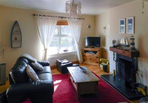 a living room with a leather couch and a fireplace at Castle Cottage By The Beach in Greencastle