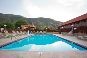 a swimming pool with chairs and mountains in the background at Glenwood Springs Cedar Lodge in Glenwood Springs