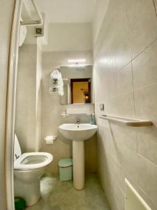 La salle de bains est pourvue de toilettes blanches et d'un lavabo. dans l'établissement La Casetta In Centro - Holiday House, à Scilla