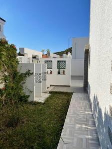 a white building with a walkway next to a yard at Magnifique villa El Haouaria-Nabeul in El Haouaria