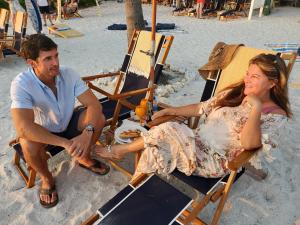 Ein Mann und eine Frau sitzen auf Stühlen am Strand in der Unterkunft Cedar Cove Resort & Cottages in Holmes Beach