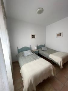 2 camas en una habitación con paredes blancas en Agradable casa rural con chimenea en interior, en Higuera de la Sierra