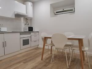 a white kitchen with a table and chairs at Apartamentos São Gião 10 in Tomar +15 photos