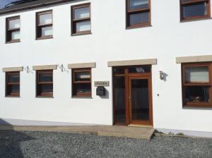 a white building with a wooden door and windows at polgoon Vineyard annex Penzance in Penzance