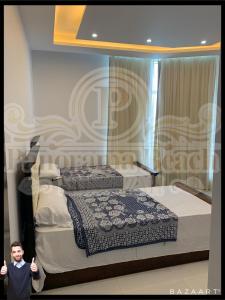 een jongen die naast twee bedden in een kamer staat bij شقق بانوراما شاطئ الأسكندرية كود 11 in Alexandrië