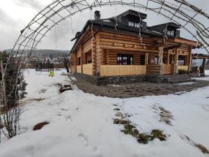 ein Blockhaus im Schnee mit einer Laube in der Unterkunft Bordeiul Legionarilor in Vatra Dornei