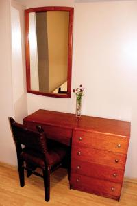 un tocador de madera con espejo y un jarrón con flores. en Hotel Splendid en Buenos Aires