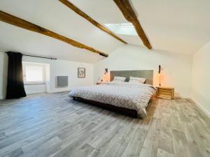 a bedroom with a bed and a wooden floor at La Carrée des Amis in Lusignan