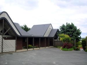 a building with a metal roof and a parking lot at Rosebank Lodge in Balclutha
