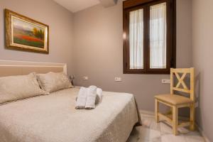 um quarto com uma cama com uma cadeira e uma janela em Precioso apartamento en Triana em Sevilha