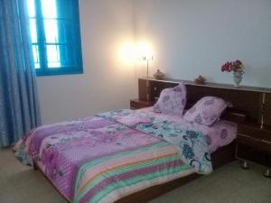 um quarto com uma cama com um cobertor roxo e almofadas em Dar Essadeg em Tataouine