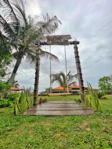 a wooden walkway leading to a building with a palm tree at Sistcep Praia Hotel in Luis Correia