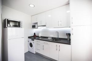- une cuisine avec des placards blancs et un lave-linge/sèche-linge dans l'établissement APARTAMENTO PASEO DE LA RIVERA, à Cordoue
