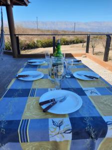 a table with plates and glasses on a blue and green table cloth at Balcones del Arroyo in Nono