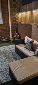 eine Terrasse mit einem Sofa und Kissen an einer Ziegelwand in der Unterkunft 1 Grange Street in Pelton