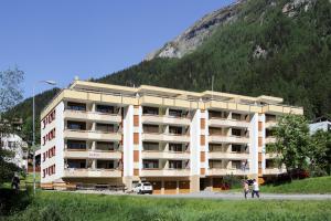 un grand immeuble en face d'une montagne dans l'établissement Baron / Baronesse Apartments, à Loèche-les-Bains