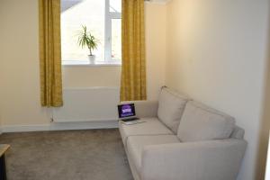 a living room with a couch with a laptop on it at Olive Tree Apartment - 2 Bedrooms Apartment - Stayseekers in Salisbury
