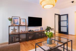 a living room with a tv and a glass table at City Garden Apartment in Poreč