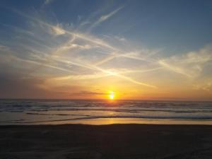 a sunset on a beach with the ocean at Tillicum Beach Motel - Formerly Deane's Oceanfront Lodge in Yachats