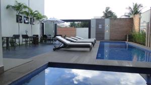 une terrasse avec une piscine et des chaises longues à côté d'un bâtiment dans l'établissement Planaltos Palace Hotel, à Goianésia