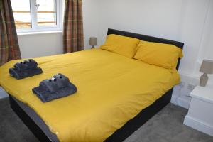 sypialnia z łóżkiem z żółtą pościelą i 2 ręcznikami w obiekcie Willow Tree 1 bed Apartment - STAYSEEKERS w mieście Salisbury