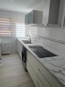 cocina blanca con fregadero y lavavajillas en Precioso apartamento a 50 metros de la playa, en Melilla