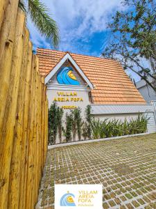 a building with a sign in front of a fence at VILLAM AREIA FOFA in Bombinhas