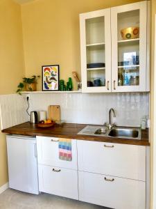 a kitchen with white cabinets and a sink at FärgLabbets Bed and Breakfast in Sunne