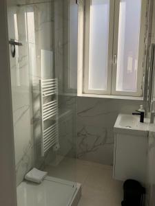 een witte badkamer met een douche en een wastafel bij Sainte Cécile 5 - T3 élégant, limineux et central in Vichy