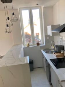 een witte keuken met een wastafel en een raam bij Sainte Cécile 5 - T3 élégant, limineux et central in Vichy